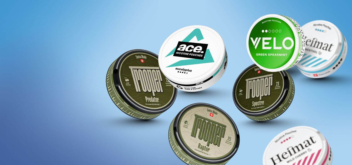 Snus ir nikotino maišeliai: Nоoper, Velo Green Spearmint ir Heimat paketai ant mėlyno fono